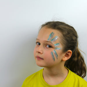 Step one, Applying glitter fixer gel to the side of the face, then adding fine turquoise and silver glitter in stripes.