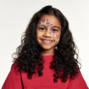 Final step, adding white dots all over the design to complete Flower Swirl face paint.