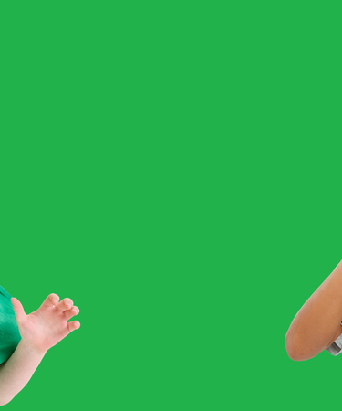Four children with green painted faces against a green background