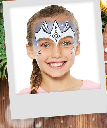 Christmas themed face paint design with polaroids of children wearing face paint against a backdrop of fir tree branches, ginger bread men and lights