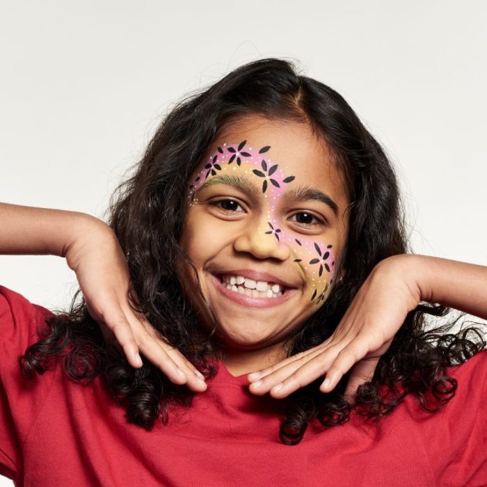 Niña con un diseño de pintura facial de remolino de flores