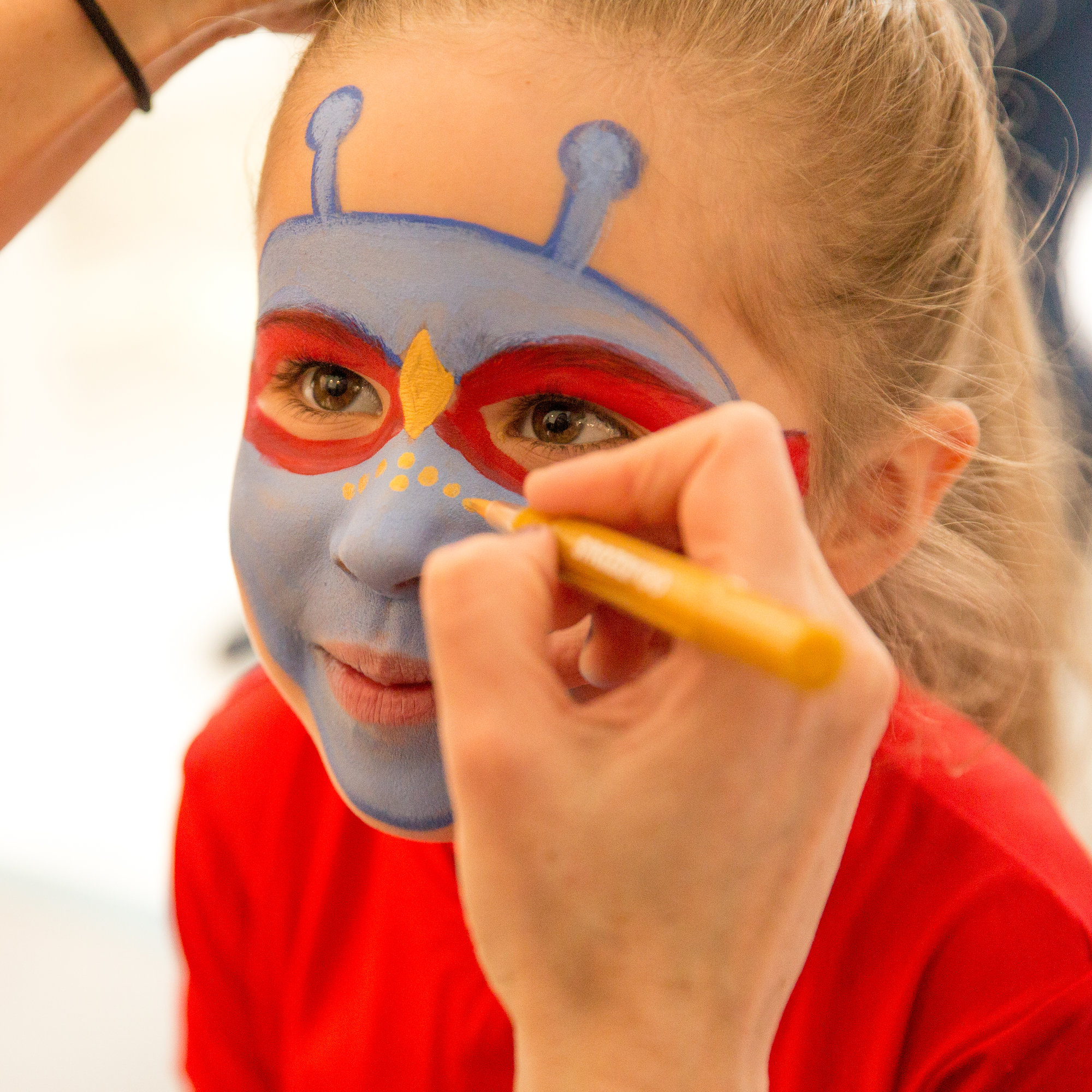 Child getting face painted as an Alien Hero